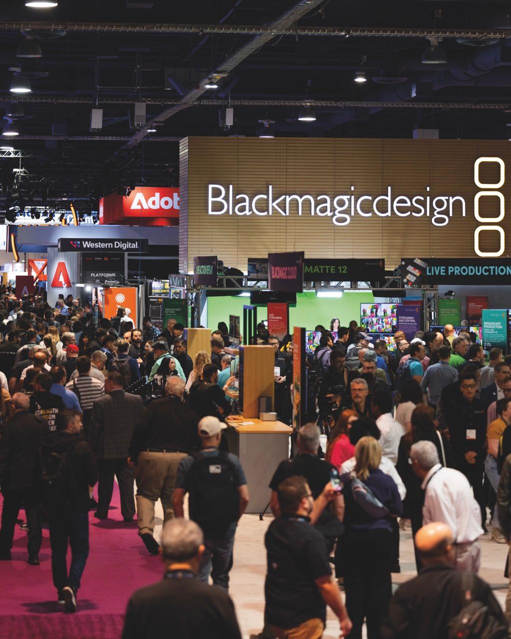 Visitors walking around a conference where a Blackmagic Design stall is set up