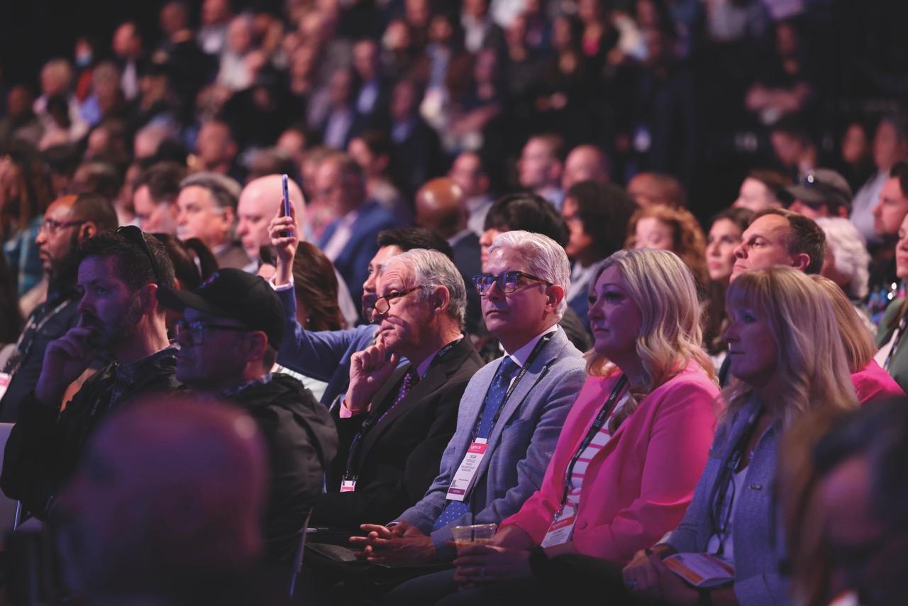 A crowd listening to a conference in low lighting