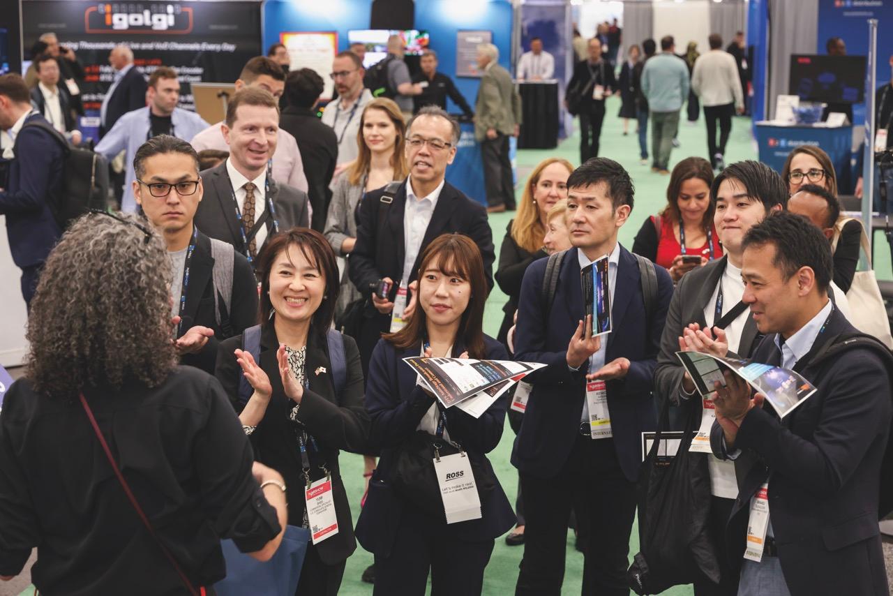 A group of people standing and listening to a conference