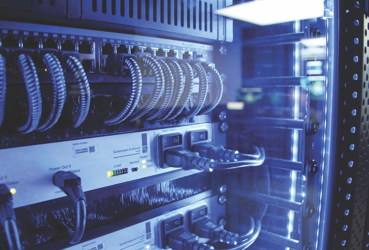 The back of a machine with wires hanging out. The lighting is blue