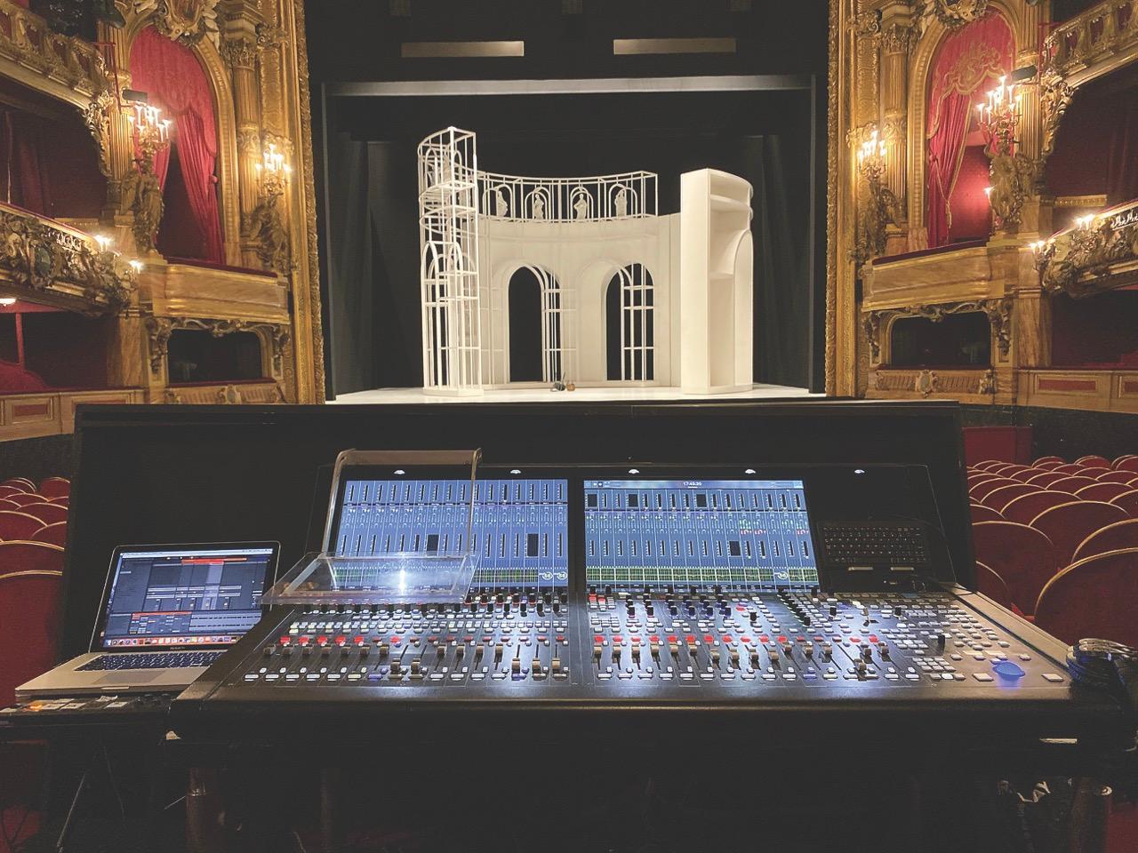 A mixing desk at the back of a theatre with a large round set-piece onstage