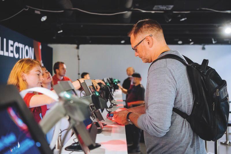 A man stands at a long desk at a conference with tablets lining the surface
