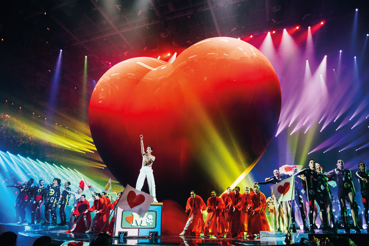 Eurovision performer on stage with a big red heart stage set up behind