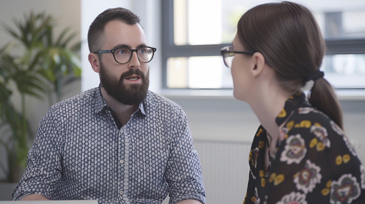 Two professionals speaking in an office, facing each other