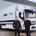 Two men standing in front of a large white truck